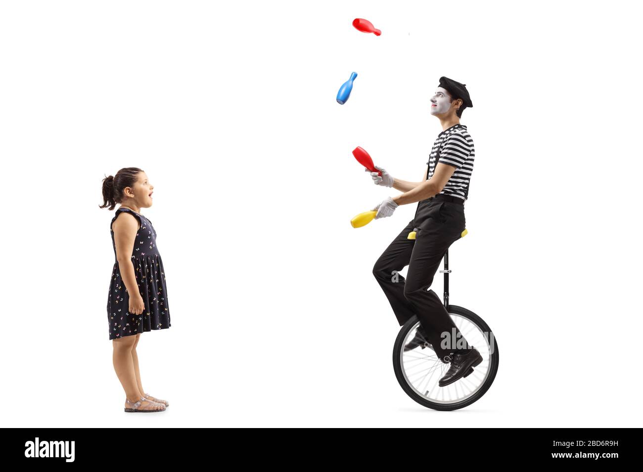 Full length profile shot of a girl watching a mime juggling and riding ...