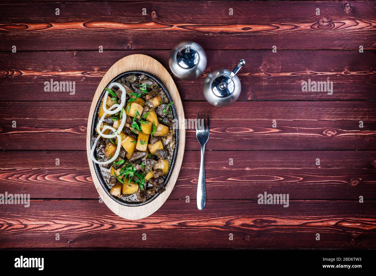 Kuurdak - traditional meat dish made in Central Asia. Serving on a hot frying pan. Top view Stock Photo