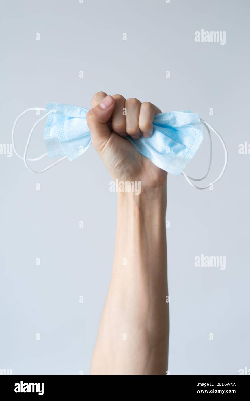 First person view of a woman holding face mask over white table background. Protective raspiratory mask for spreading virus. Close up, copy space, top view, flat lay Stock Photo