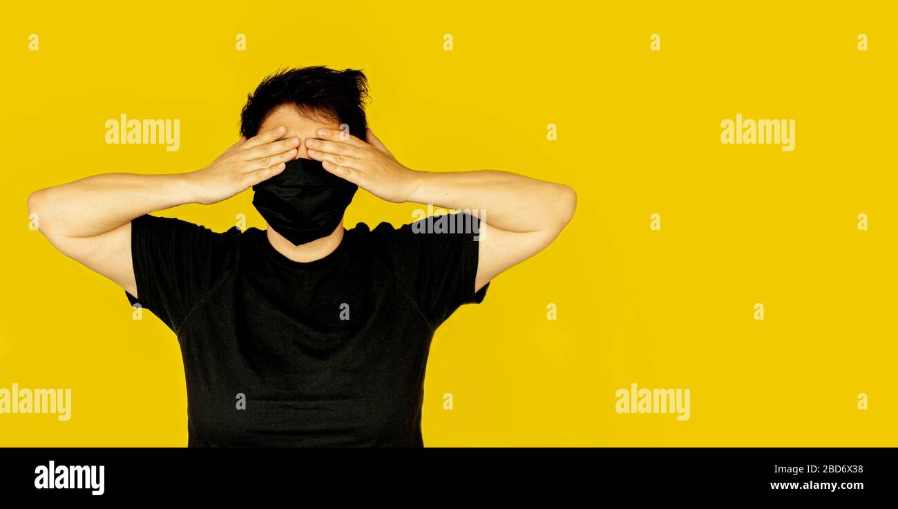 girl brunette short hair covers her face with her hands black medical mask emotion not to see Stock Photo