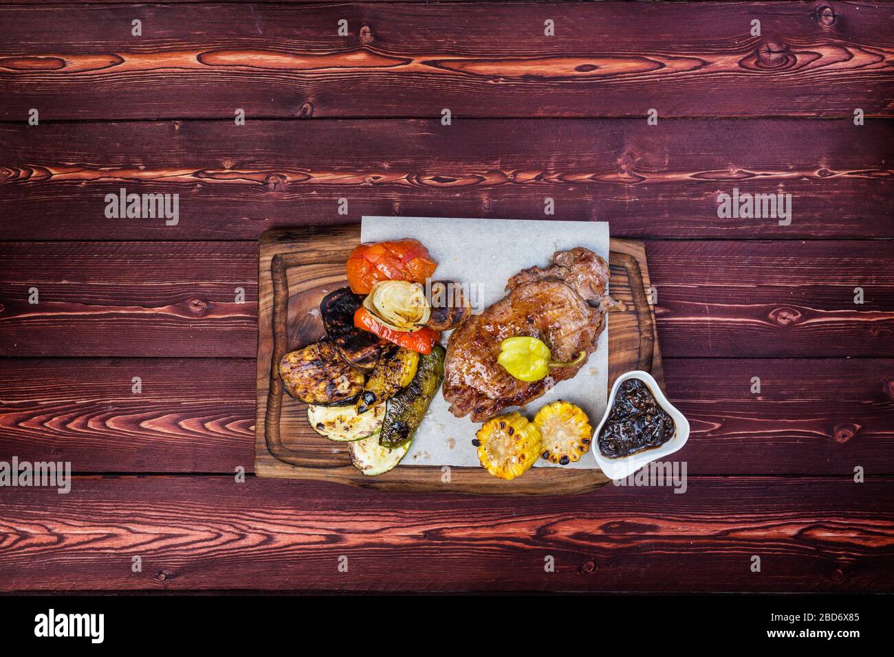 Delicious grilled steak with assorted roast vegetables and corn with sauce. Top view Stock Photo