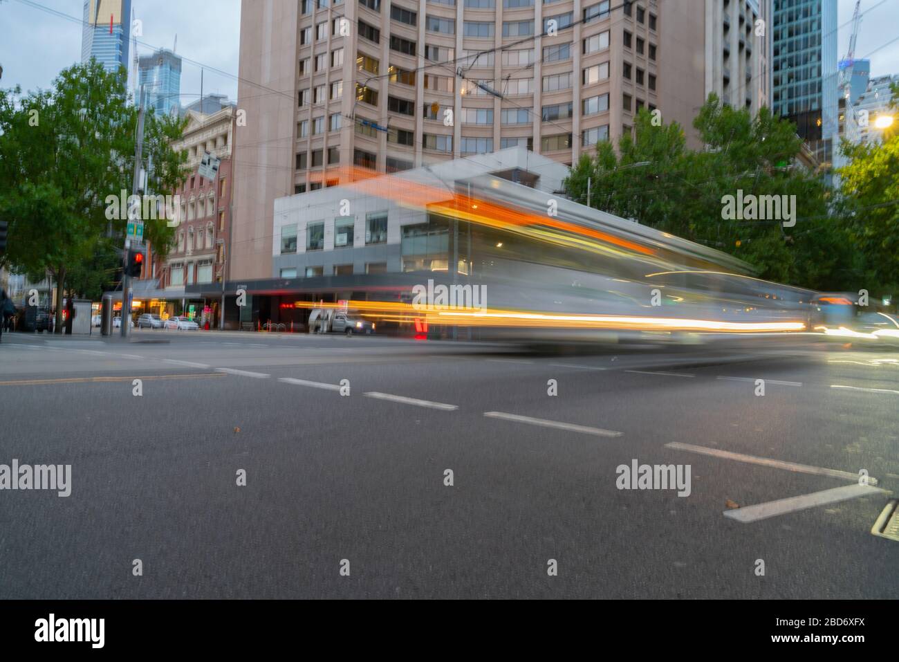 Pace of city life implied but the motion blurs and light trails of passing trams and vehicles in Melbourne downtown strreets, Australia. Stock Photo
