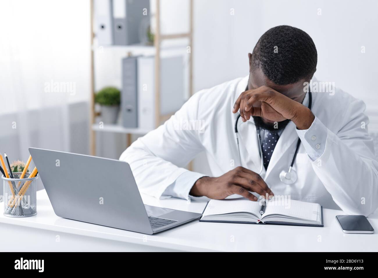 Super busy doctor having headache, sitting in office Stock Photo - Alamy