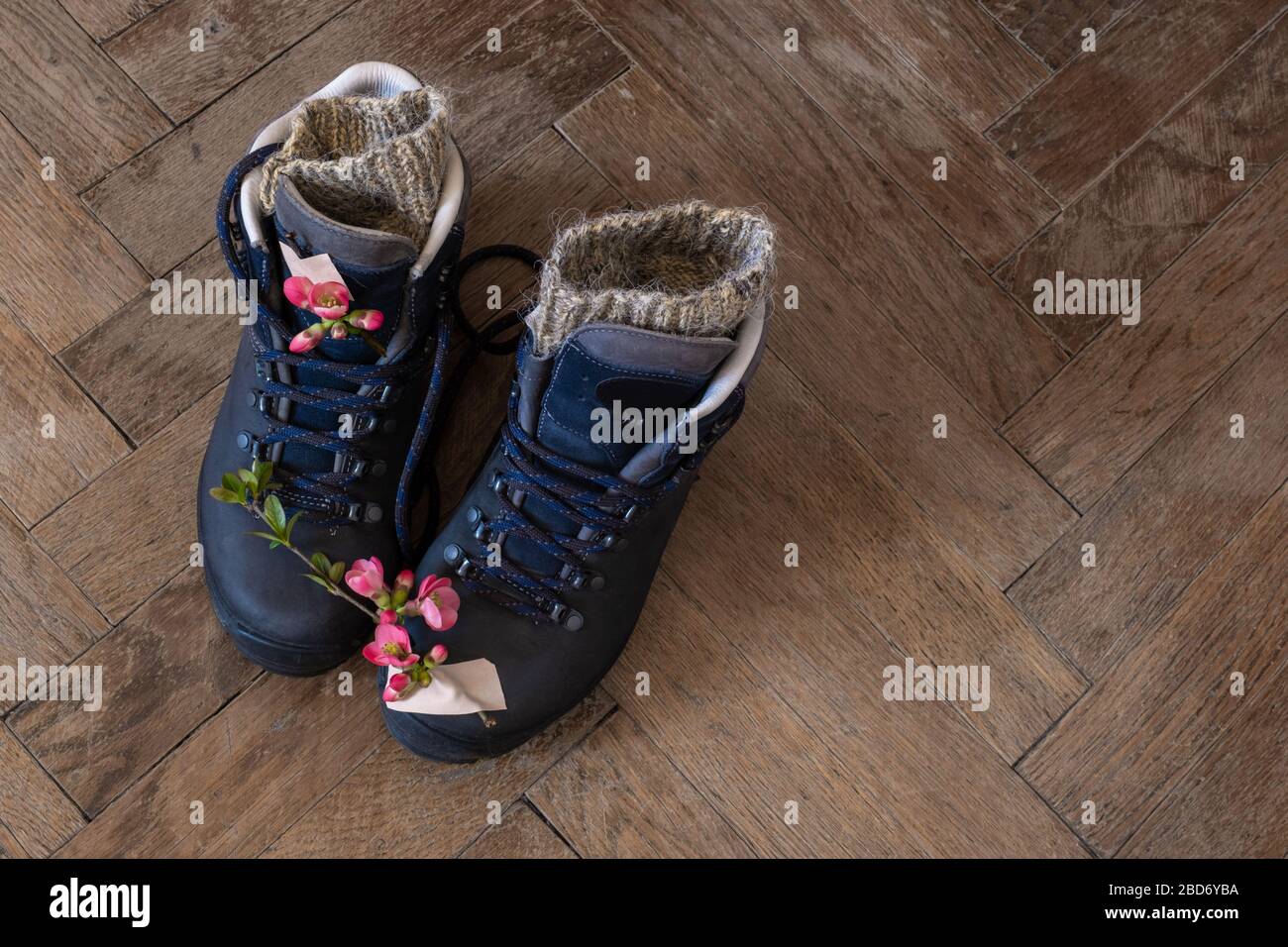 Three pair of legs in boots for hiking stand on the grey pavement. Top