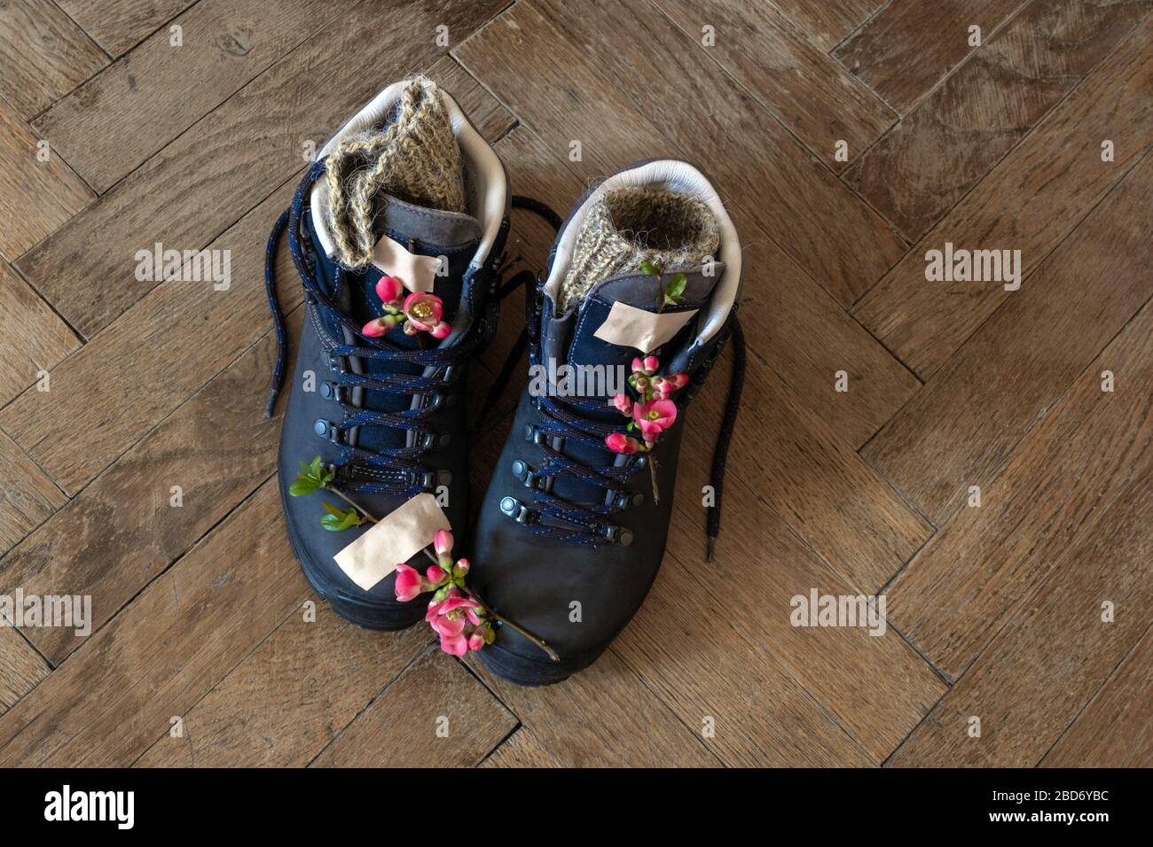Three pair of legs in boots for hiking stand on the grey pavement. Top