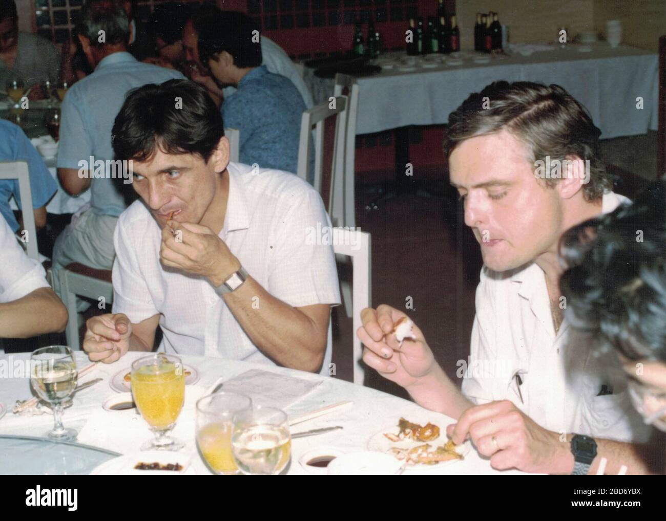 CHINA - 1989: Retro photo shows a group of caucasian - European businessmen and Chinese businessmen have a working lunch. Stock Photo