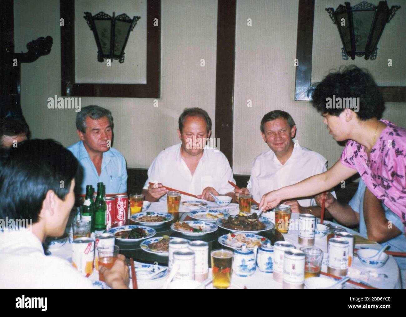 CHINA - 1989: Retro photo shows a group of caucasian - European businessmen and Chinese businessmen have a working lunch with chop-sticks. Stock Photo