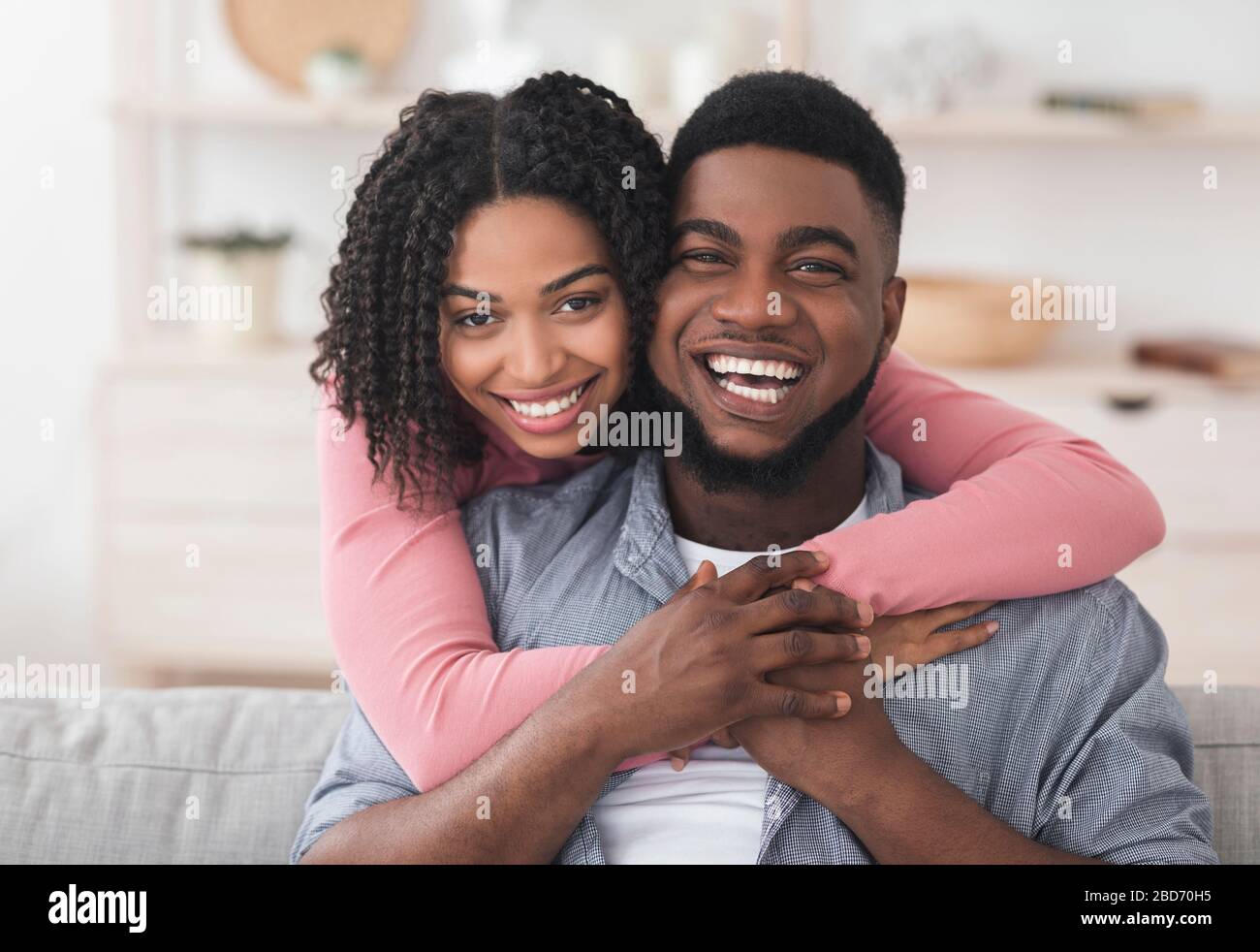 Loving African American Couple Hugging At Home And Looking At Camera ...