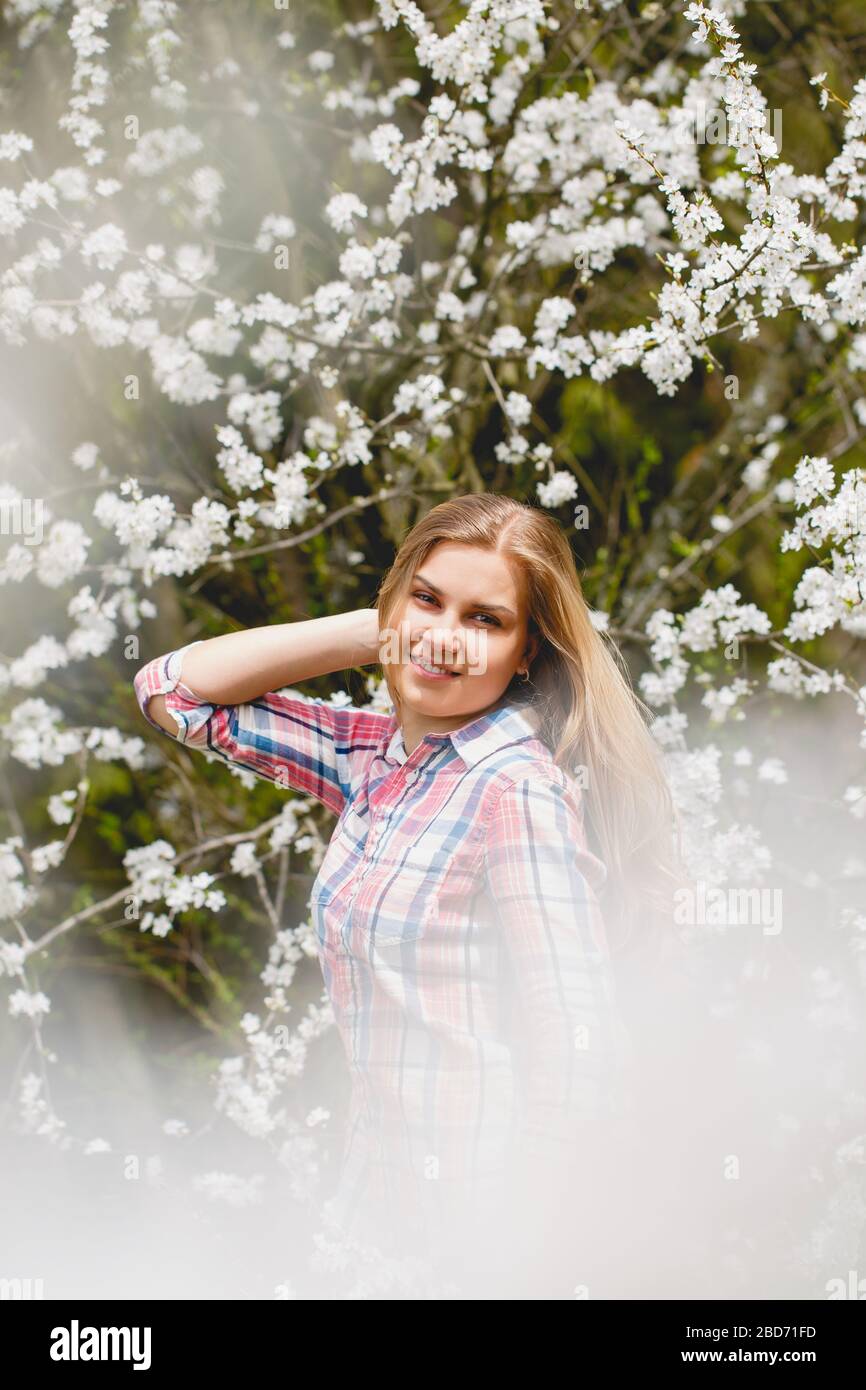 Beautiful girl in flowering trees in early spring. Bright sun and ...