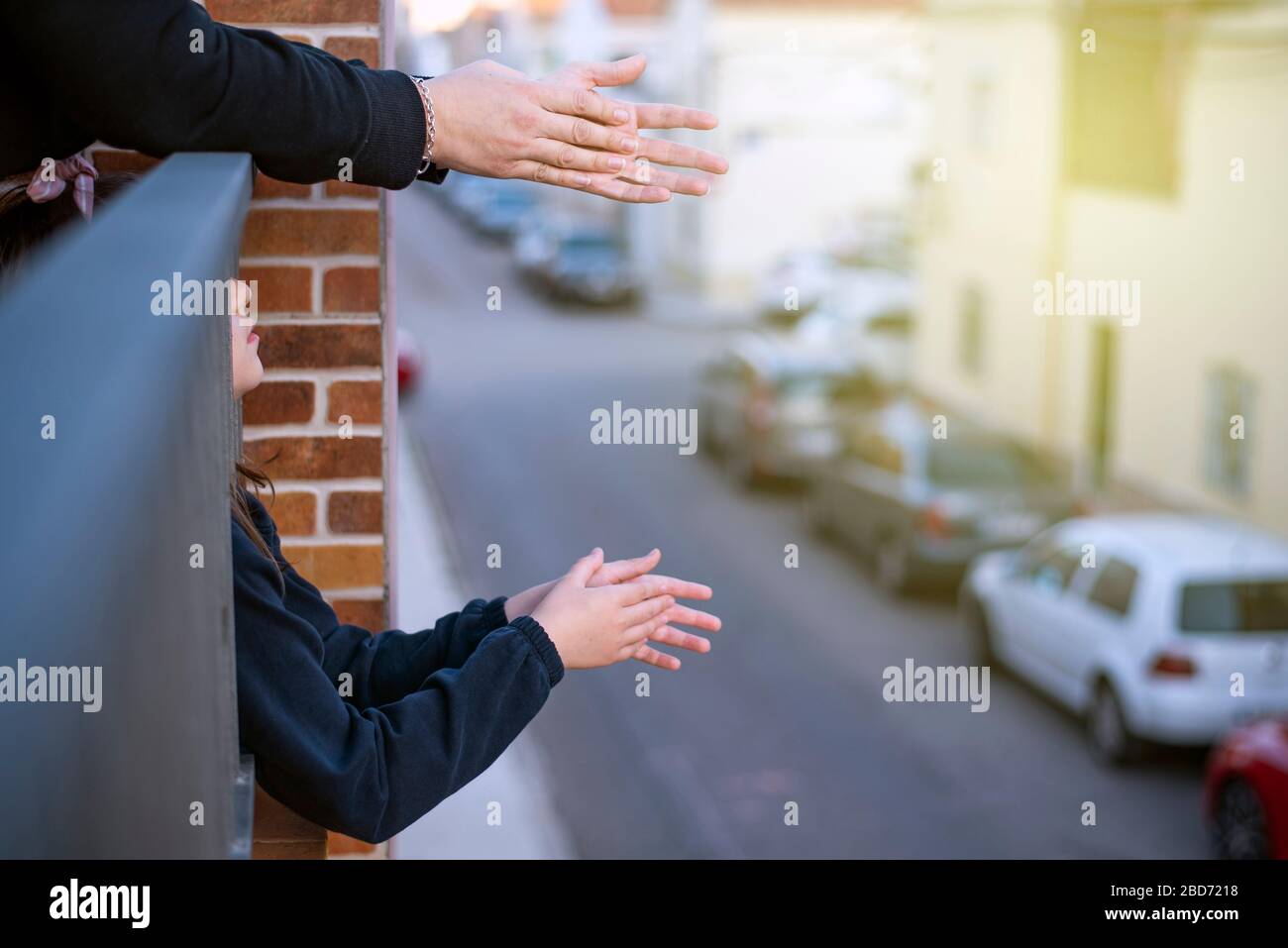 hands clapping on a balcony overlooking a street with the lights on Stock Photo