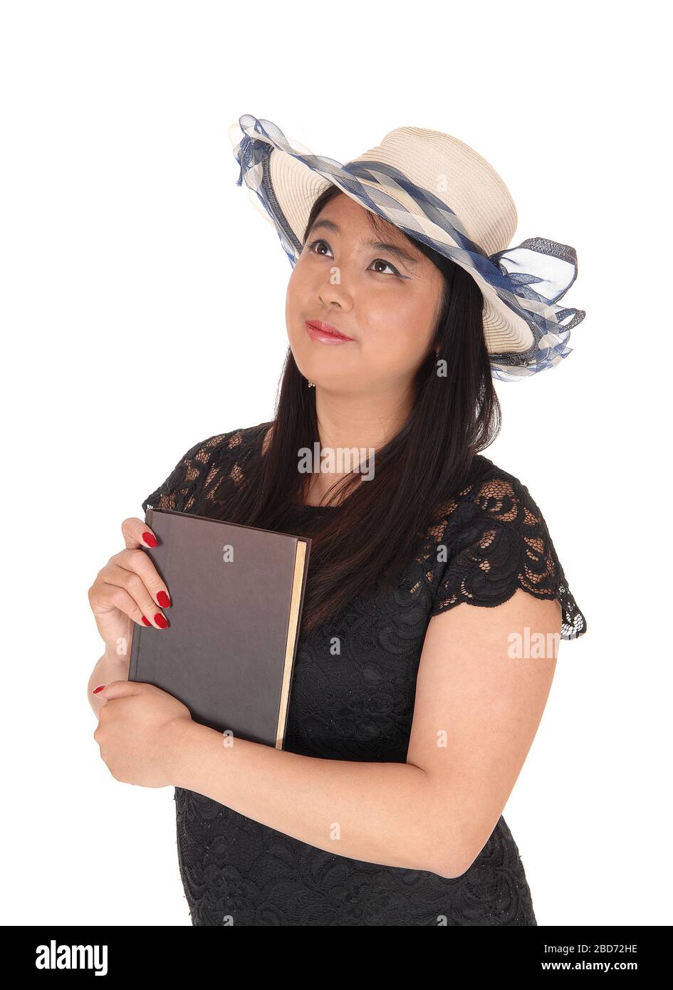 A gorgeous young Chinese woman standing in a black dress and long black hair wearing a summer hat, isolated for white background Stock Photo