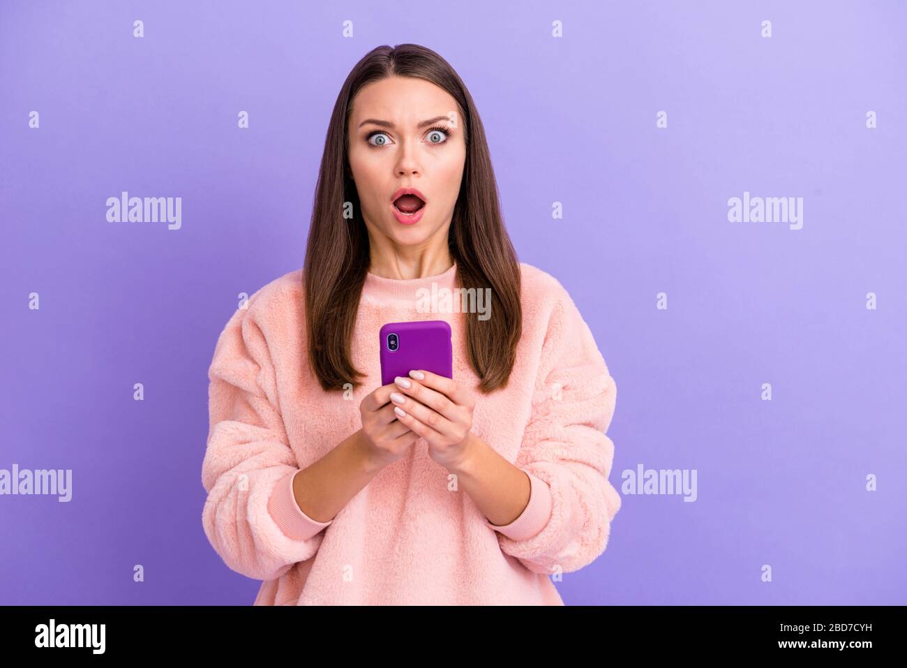 Photo of crazy blogger lady holding telephone hands open mouth bot believe eyes read bad news boyfriend sms wear casual soft sweater isolated purple Stock Photo