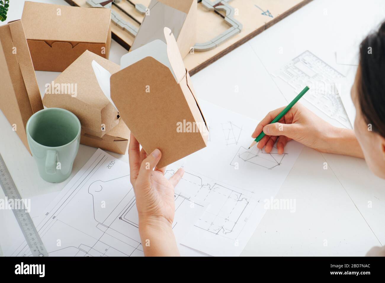 Box maker working behind a table, holding box in her hand Stock Photo ...