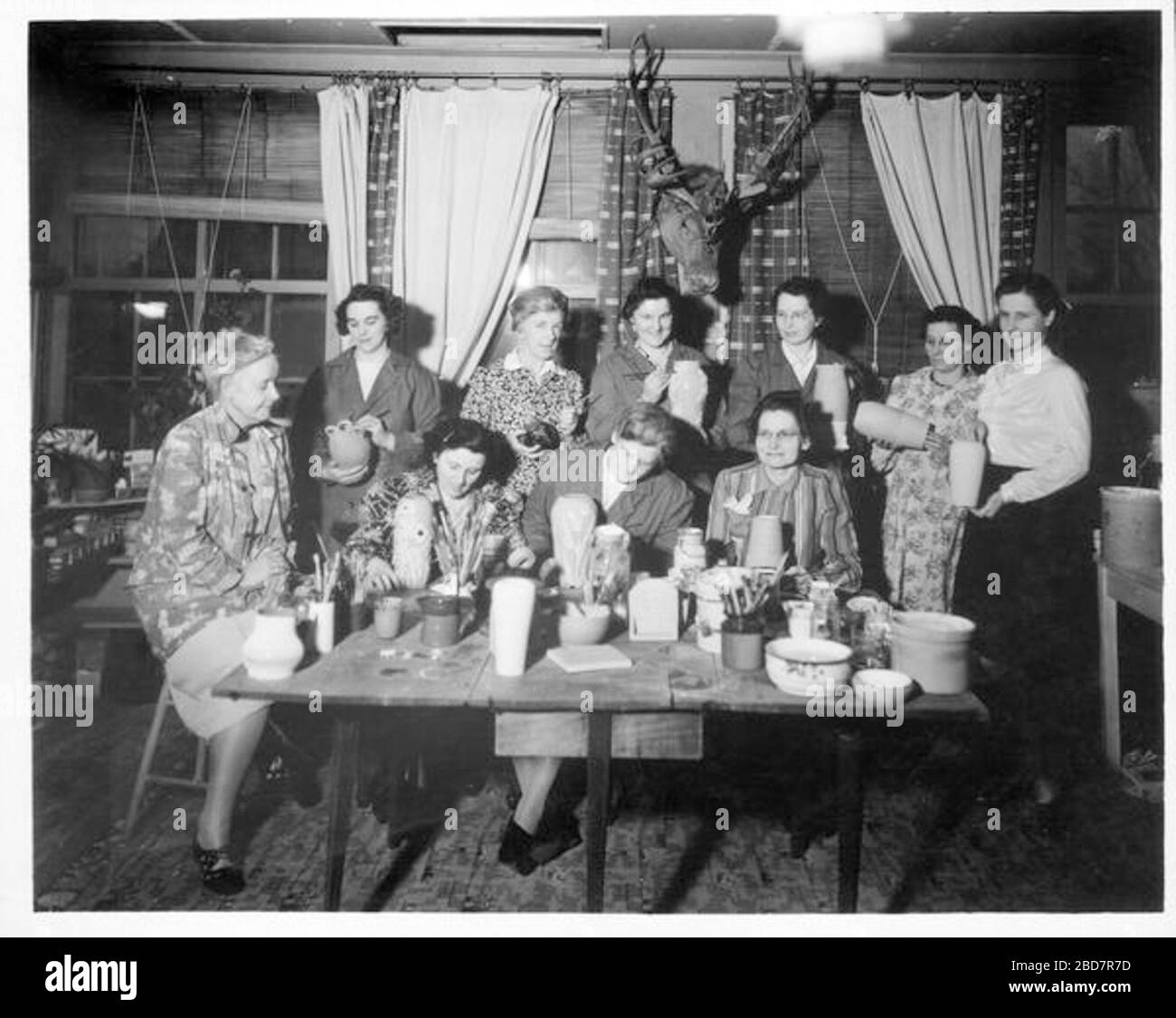 'English: Image of Hagen seated on a stool next to seated and standing pottery class students in Mahone Bay.; [194-]; University of Waterloo Library. Special Collections & Archives. Alice Mary Hagen fonds. Hagen with pottery class students. WA4 11 002.; Unknown author; ' Stock Photo