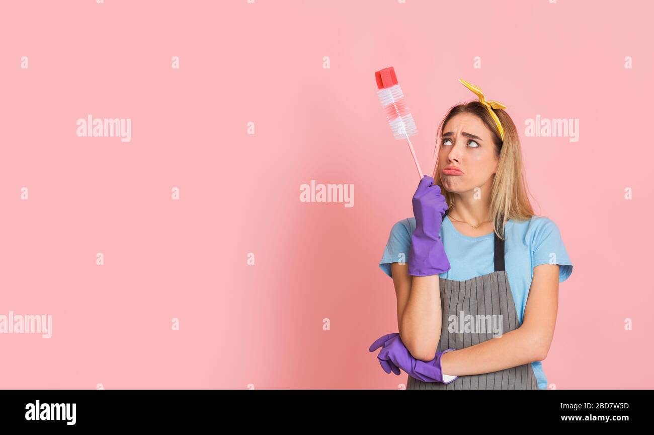 Housewife with rubber gloves looks at brush Stock Photo