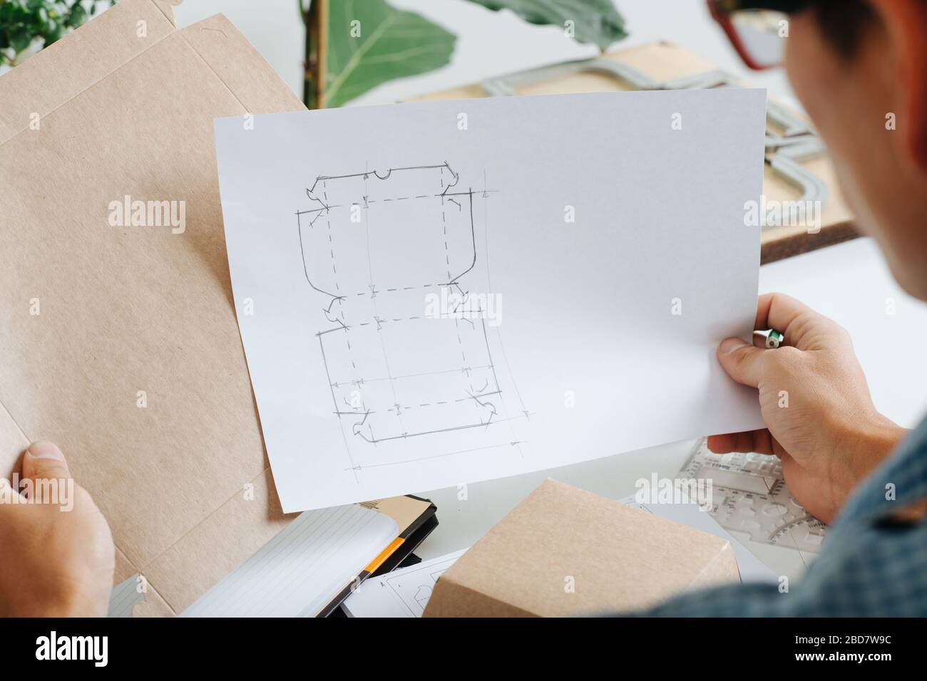 Box maker looking closely at box schematics, comparing it to template ...