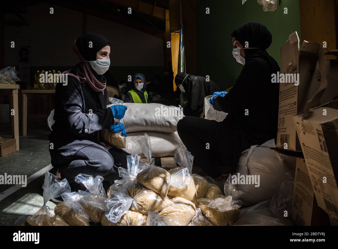 Baalbek, Lebanon, 7 April 2020. People pack food boxes, for 2000 Lebanese families struggling to make ends meet during financial crisis and the global coronavirus pandemic, at a sports hall converted into a food distribution center by Shia group, Hezbollah. Elizabeth Fitt Credit: Elizabeth Fitt/Alamy Live News Stock Photo