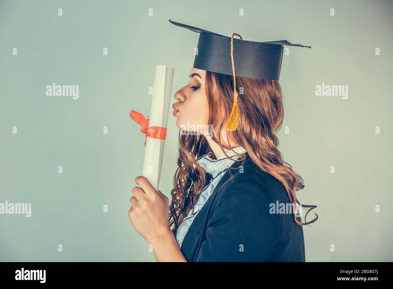 Portrait closeup beautiful happy glad latina graduate, graduated student  girl young woman in cap gown turning kissing her diploma scroll isolated  gree Stock Photo - Alamy, image size:1300x956