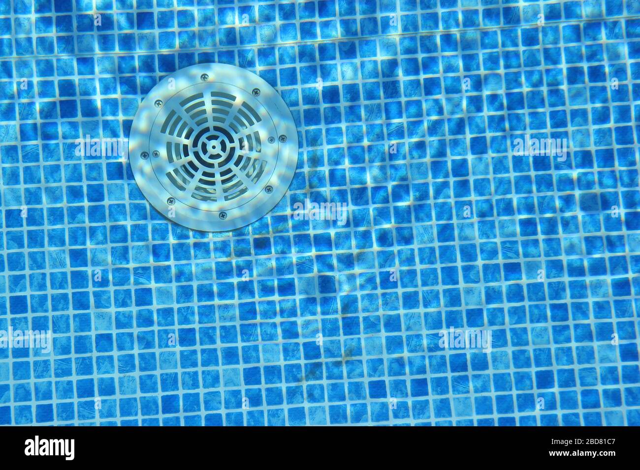 Drain hole in the pool with blue tile. Pool filtration system. Clean