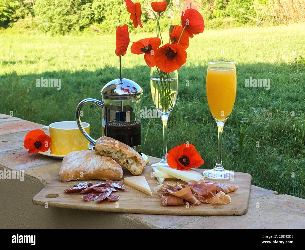 breakfast with Jamon, juice, coffee, cheese, bread and poppy flowers Stock Photo