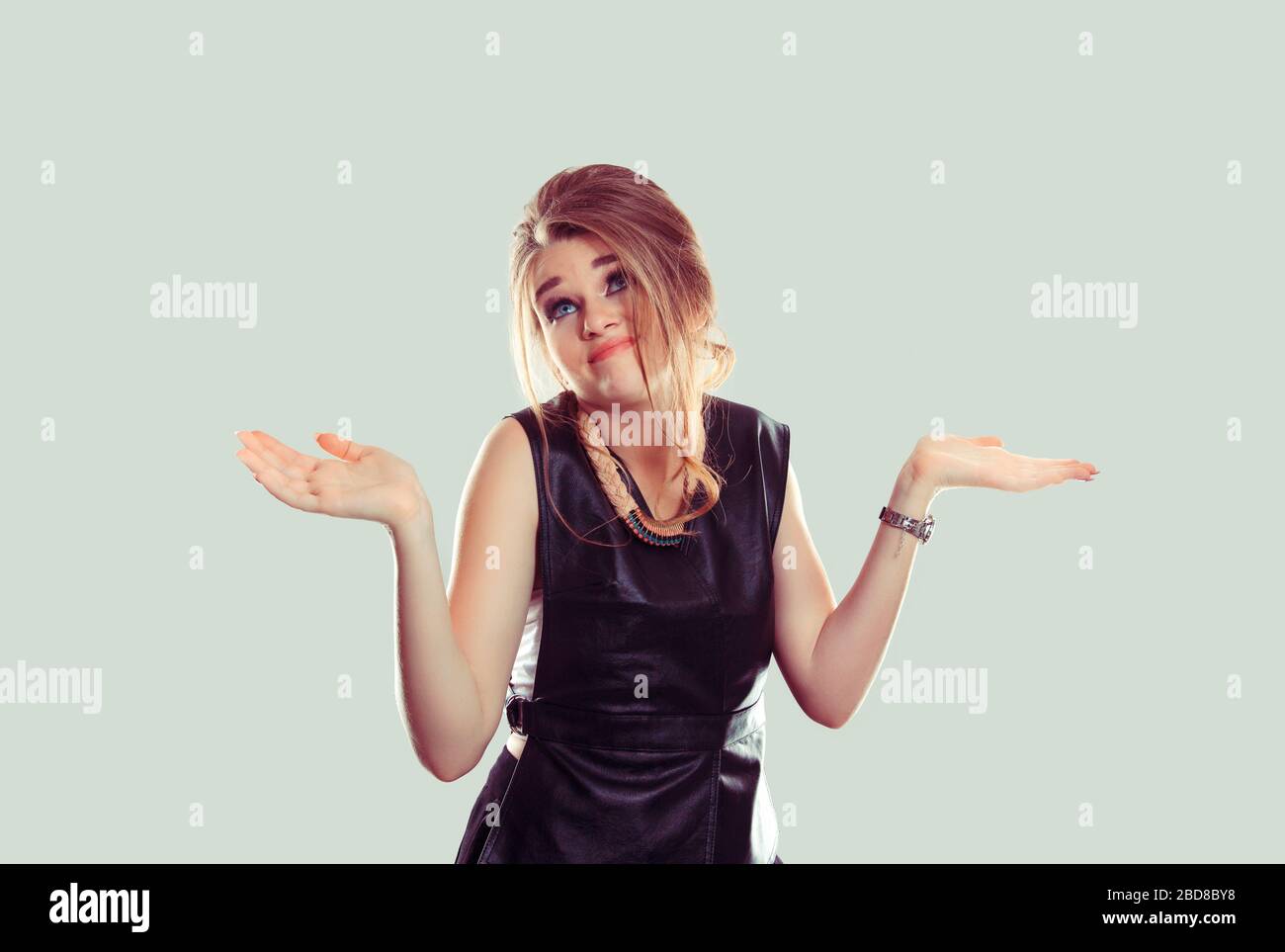I don't know. Portrait dumb looking woman arms out shrugs shoulders who cares so what I don't know isolated on light green wall background. Negative h Stock Photo