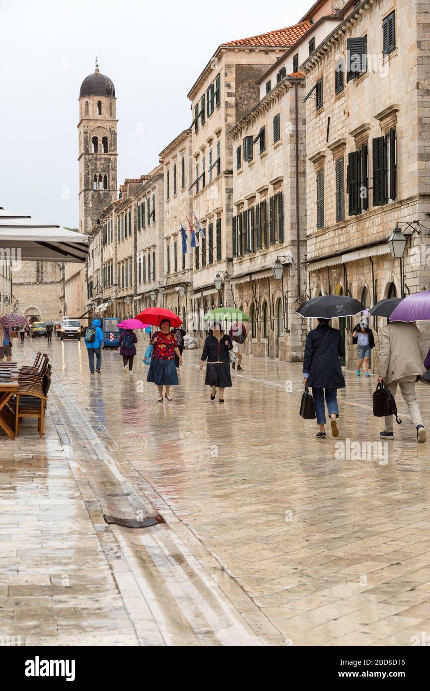 Tourists with umbrellas, walking, through the streets of  Old Town, Dubrovnik in the rain. Stock Photo