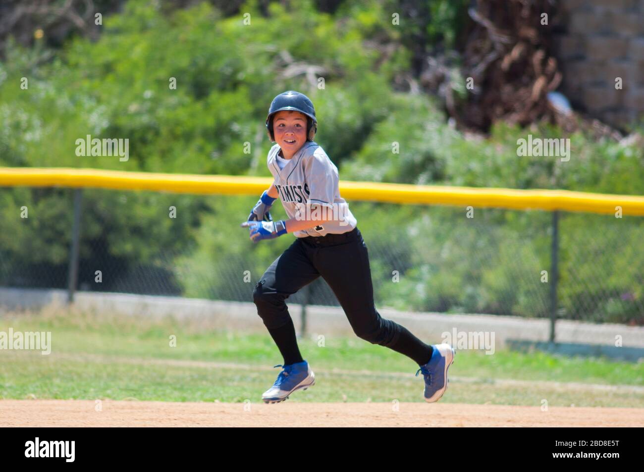 Little League baseball player running with big smile Stock Photo