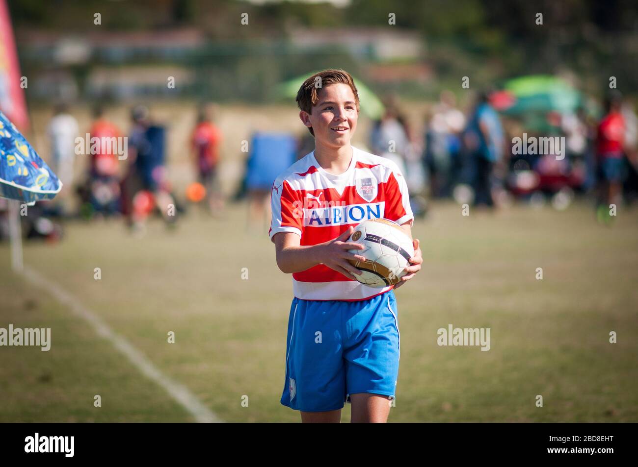 Teen soccer player smiling, holding ball and ready for a throw in Stock Photo