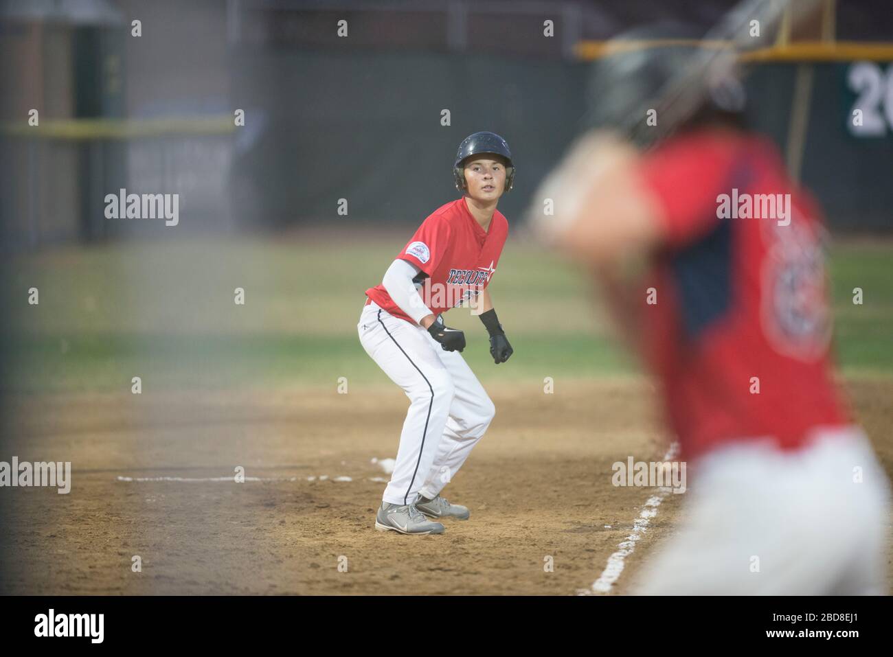 Teen baseball player leading off third base Stock Photo