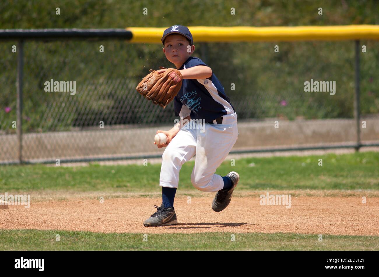 Little League infielder about to throw the ball to first base Stock Photo