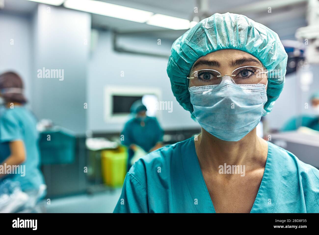 Close Up Of A Surgeon Woman Looking At Camera With Colleagues