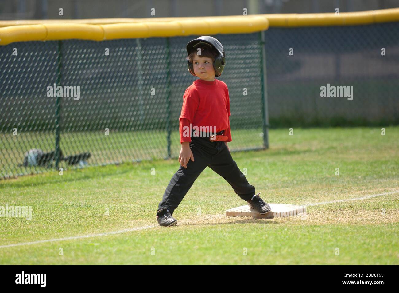Young boy smirking on third base on the TBall field Stock Photo