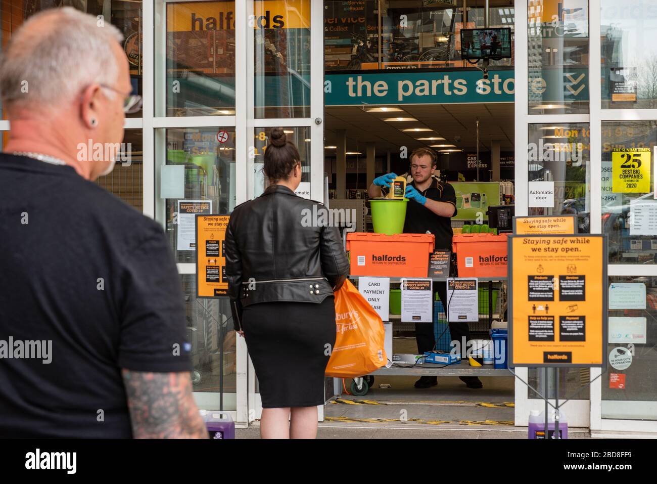 Customers at a Halfords store queue during the coronavirus (Covid-19) outbreak, April 2020, and are not allowed inside, but are served at the doorway Stock Photo