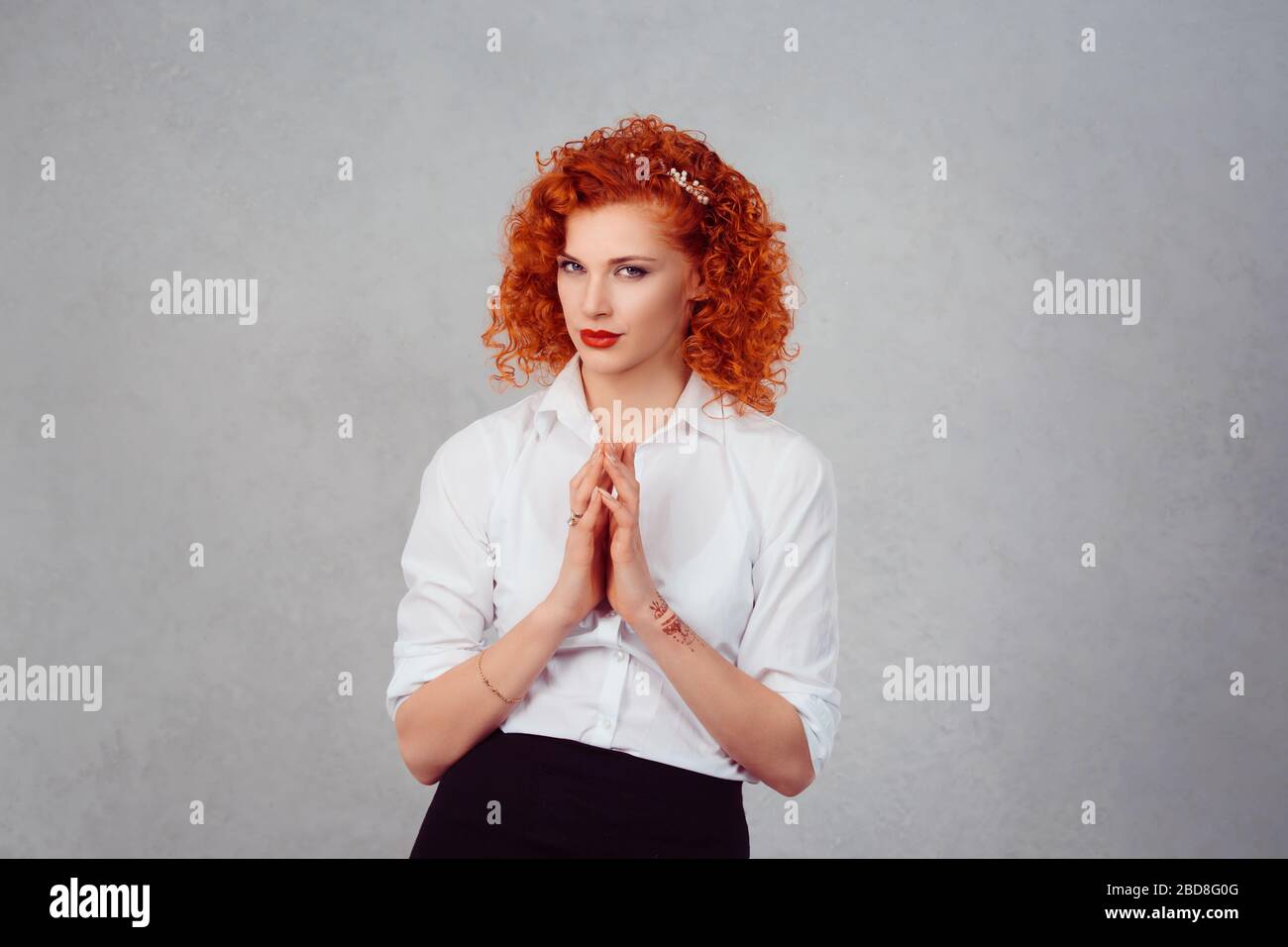 Plotting. Closeup portrait sneaky, sly, scheming young redhead woman plotting revenge plan, prankster isolated on gray wall background. Negative human Stock Photo