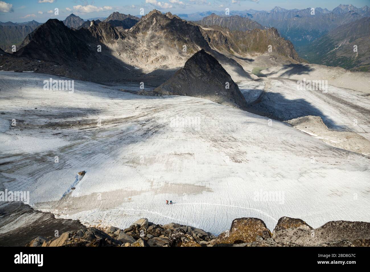 People hike across Snowbird Glacier, as seen from Glacier Pass, Talkeetna Mountains, Alaska. Stock Photo