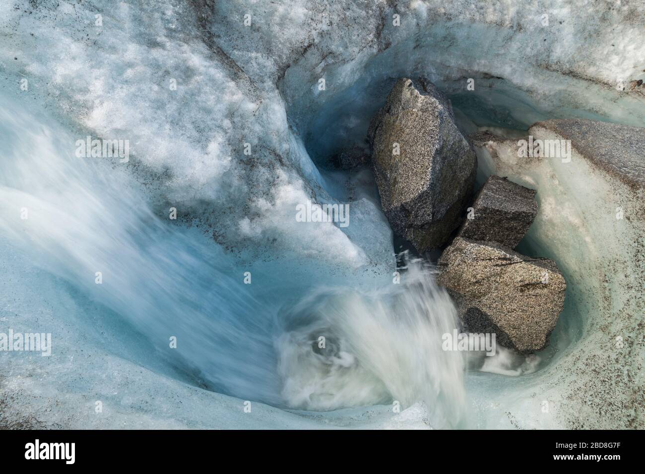 Glacial meltwater stream with boulders deposited by rockfall on the surface of Snowbird Glacier, Talkeetna Mountains, Alaska. Stock Photo