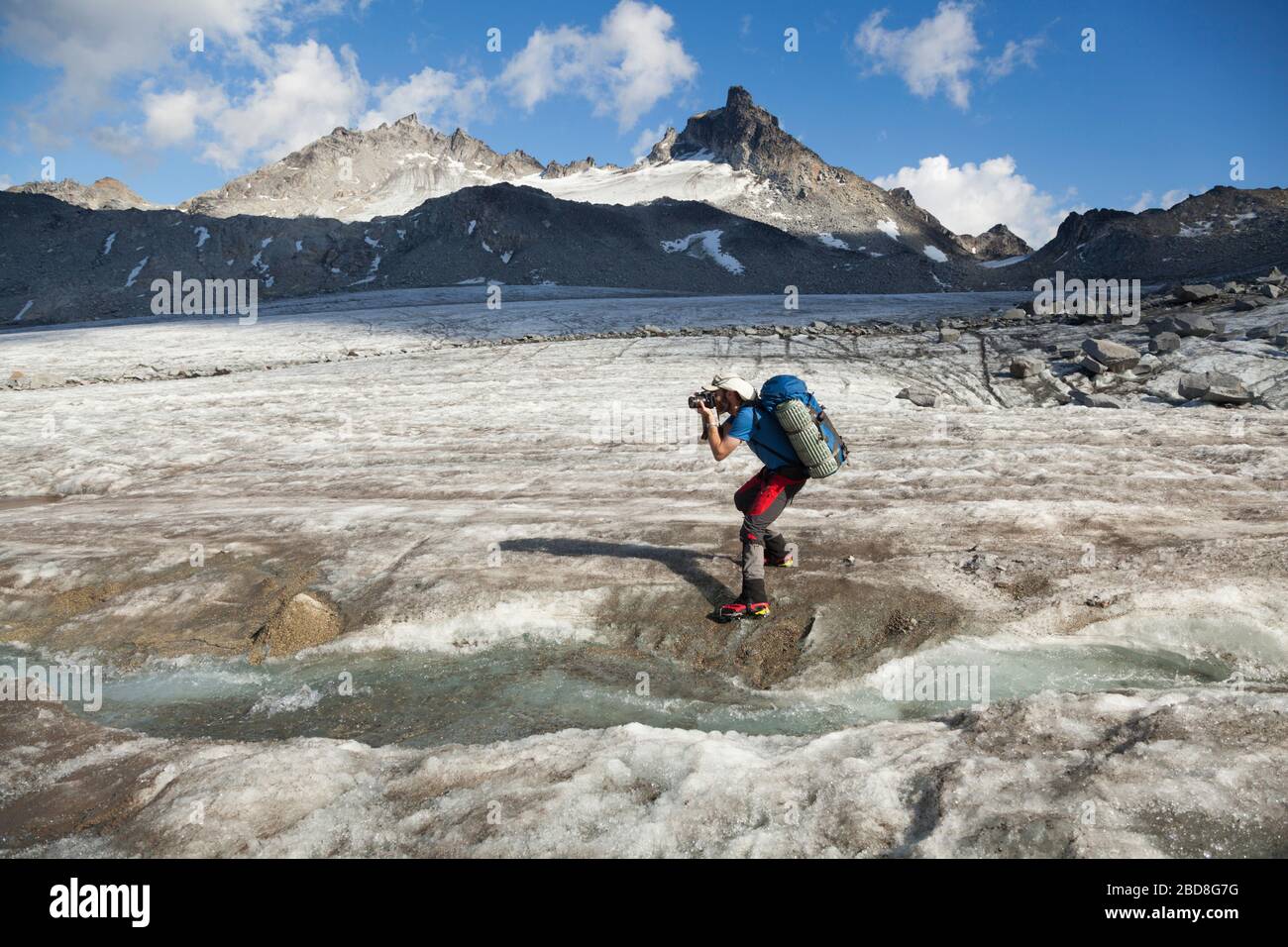 A man photographs a meltwater stream on the surface of Snowbird Glacier, Talkeetna Mountains, Alaska. Stock Photo