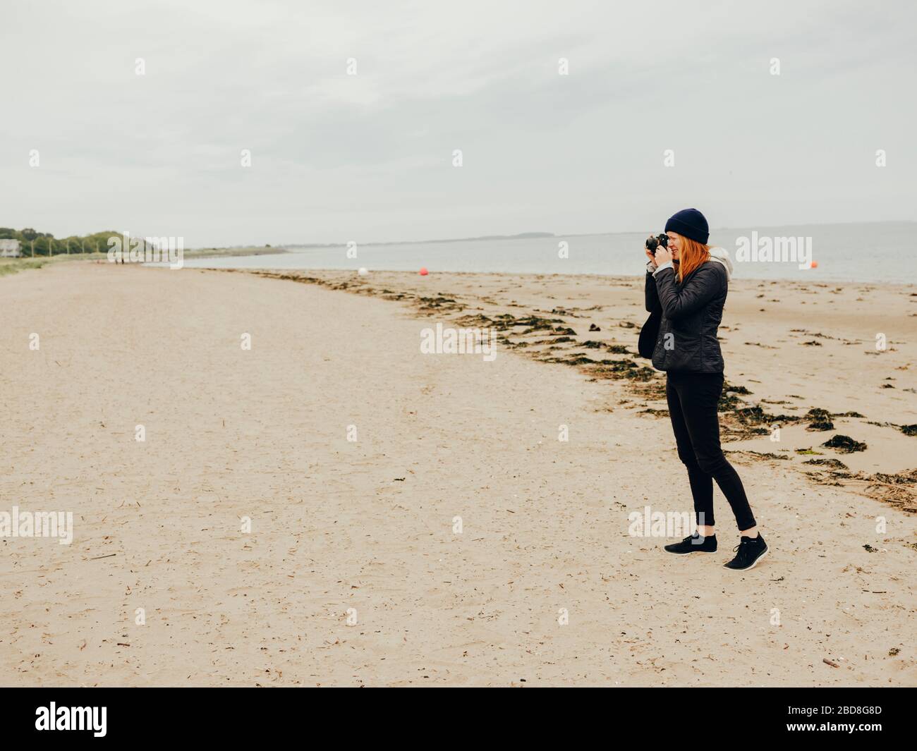 Woman taking photos on beach in Scotland Stock Photo