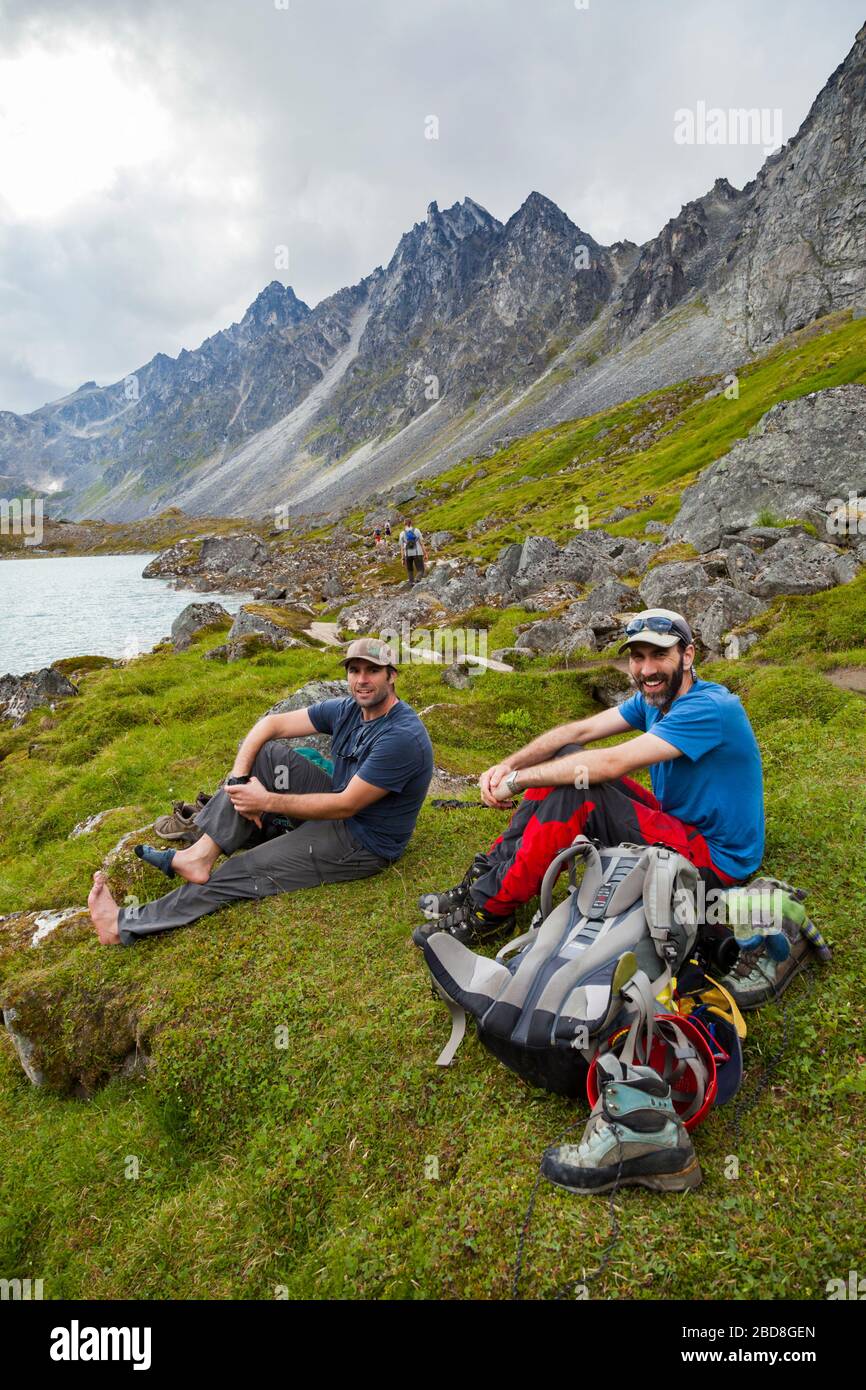 Hikers relax on the shore of Upper Reed Lake, Talkeetna Mountains, Alaska. Stock Photo