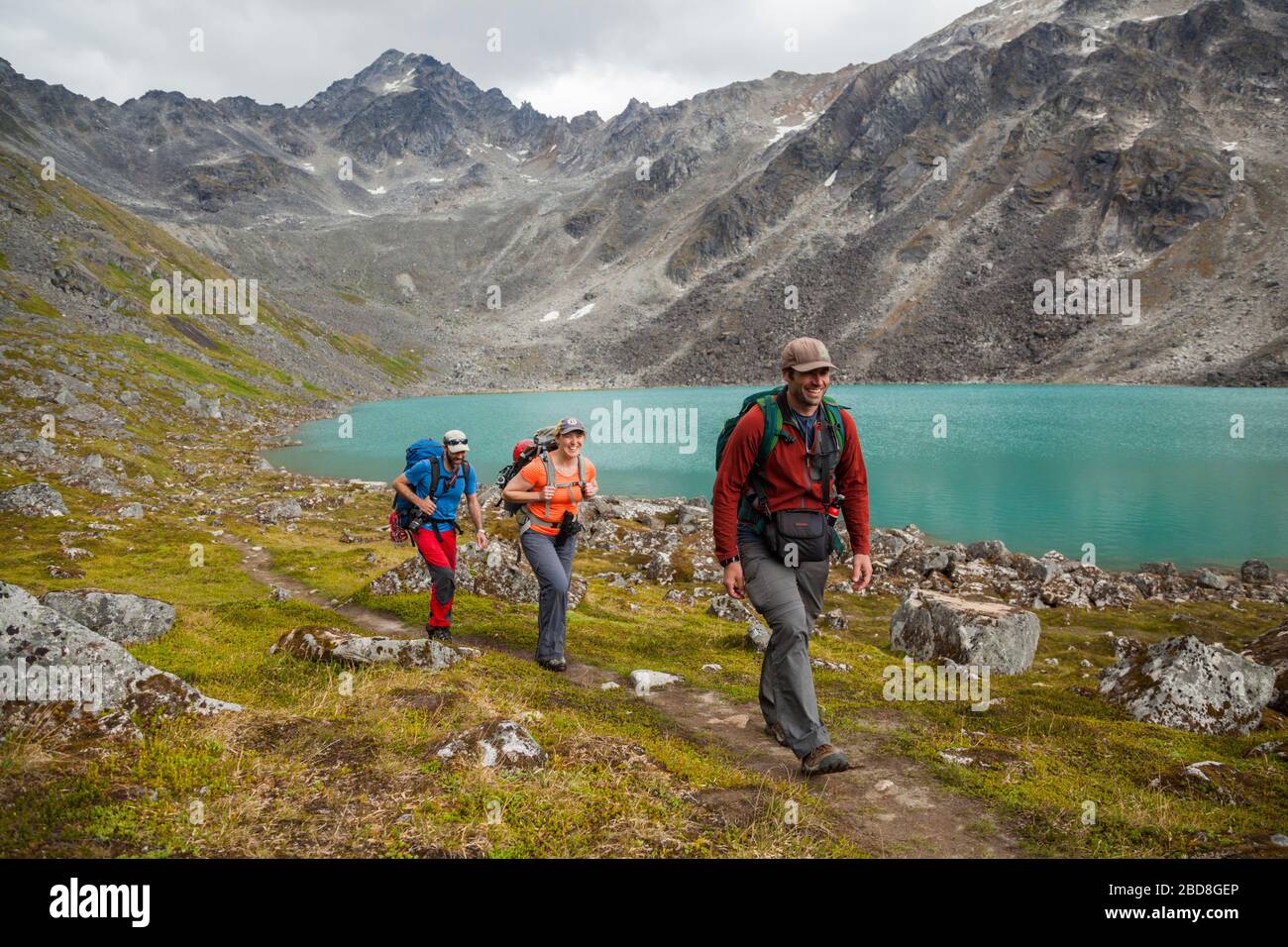People hike along the shore of Upper Reed Lake, Talkeetna Mountains, Alaska. Stock Photo