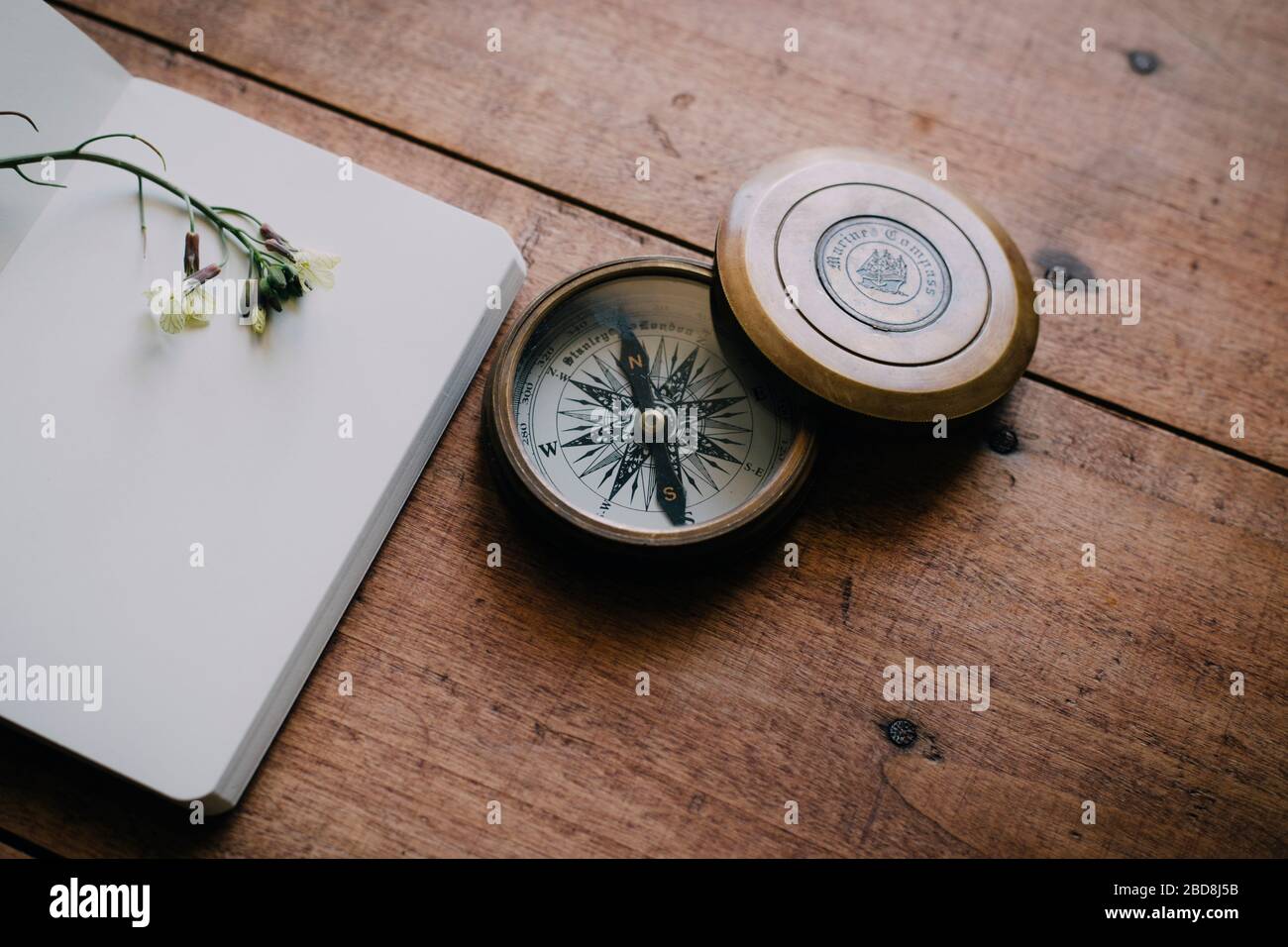 Old compass on wooden table next to notebook Stock Photo