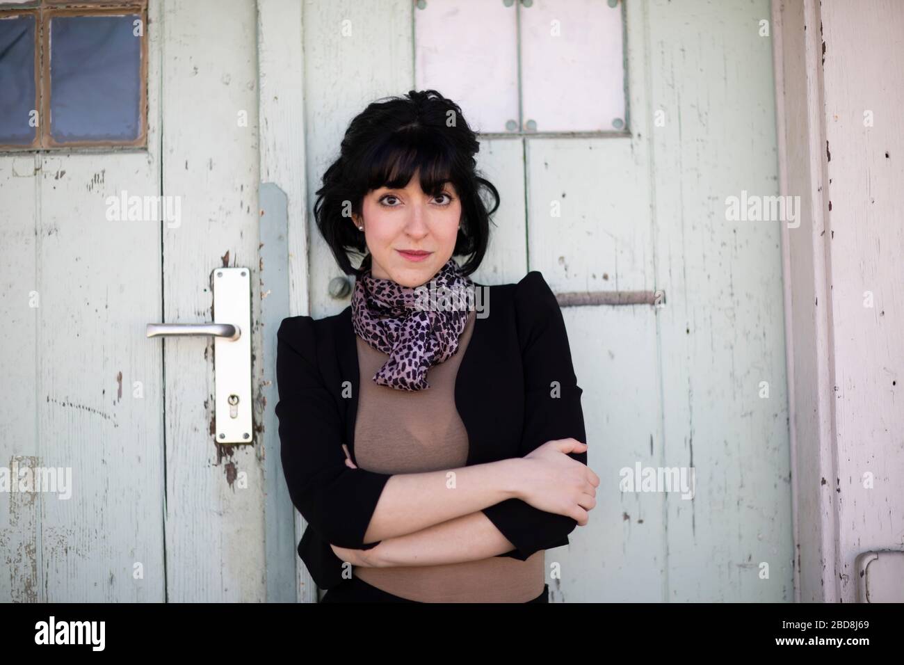 young woman with black hairs standing in front of a door Stock Photo