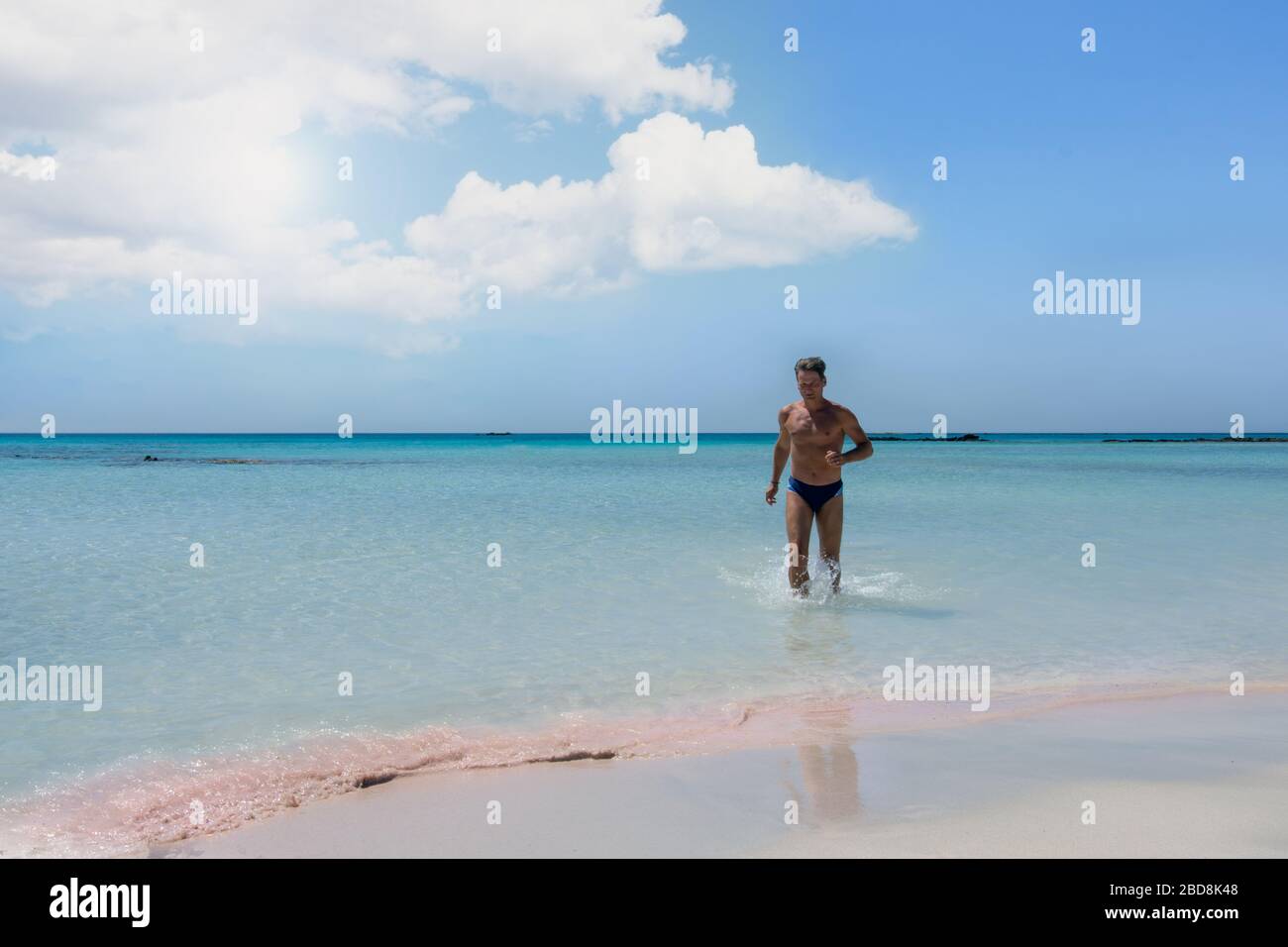 Landscape with sea and man enjoying water on Elafonisi beach in Greece Stock Photo