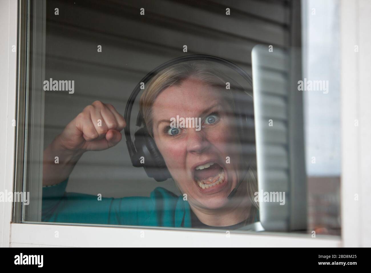 employee working from home looks crazy or mad stuck inside window Stock Photo