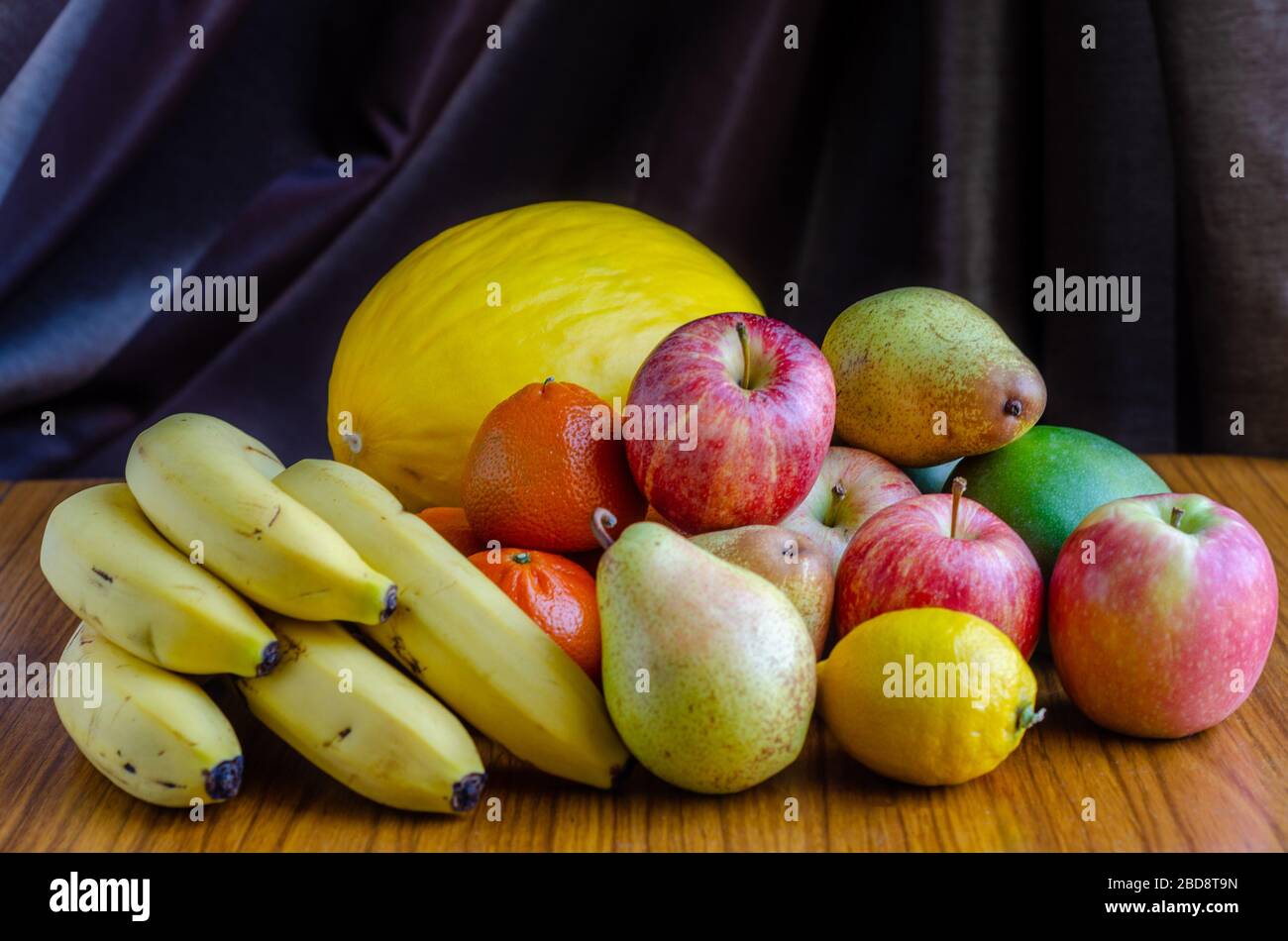 A still life shot with an assortment of different types of fruit including apples, mandarin oranges, melon, banana, pears, mango, lemon Stock Photo