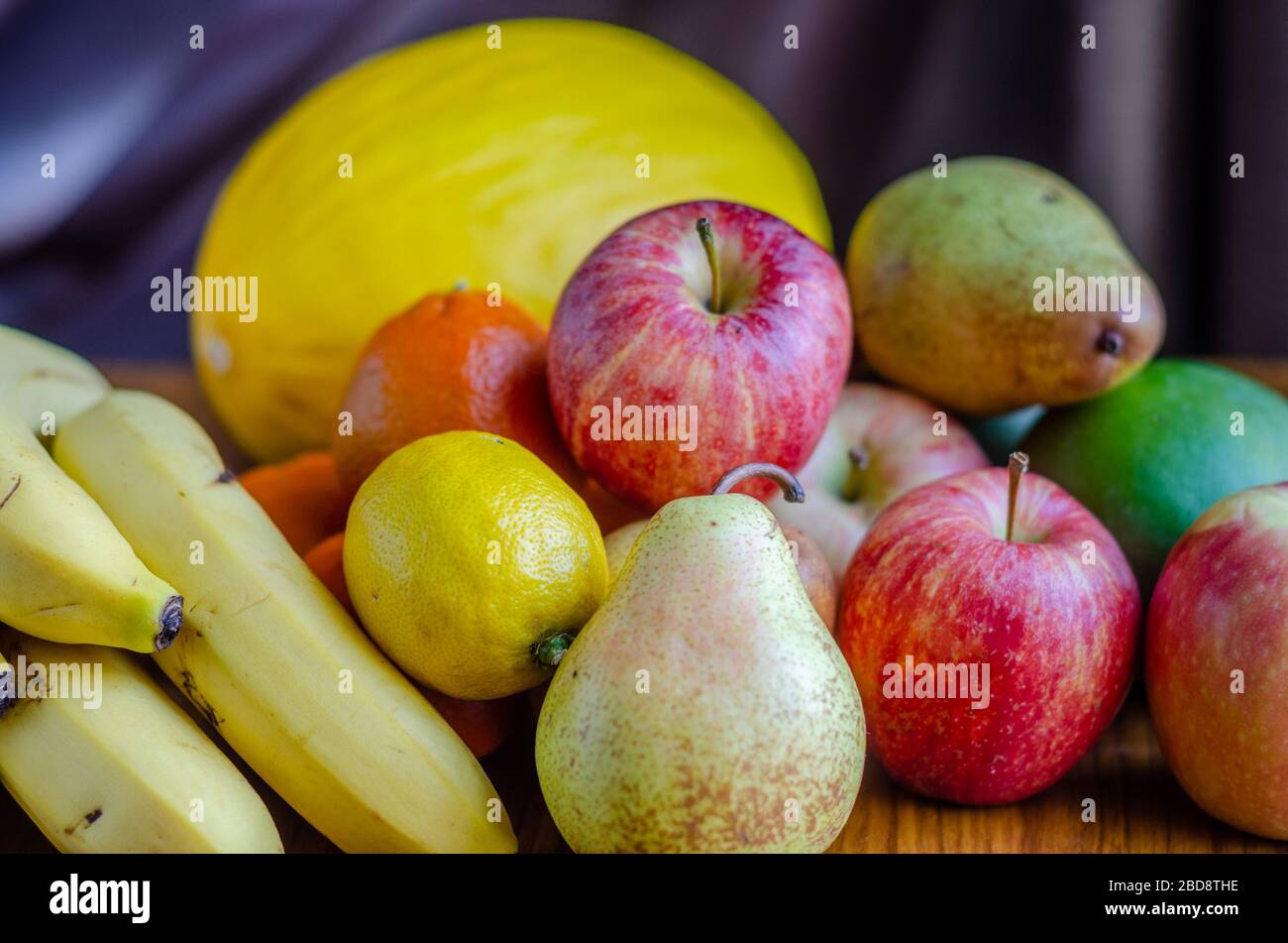 A still life shot with an assortment of different types of fruit including apples, mandarin oranges, melon, banana, pears, mango, lemon Stock Photo