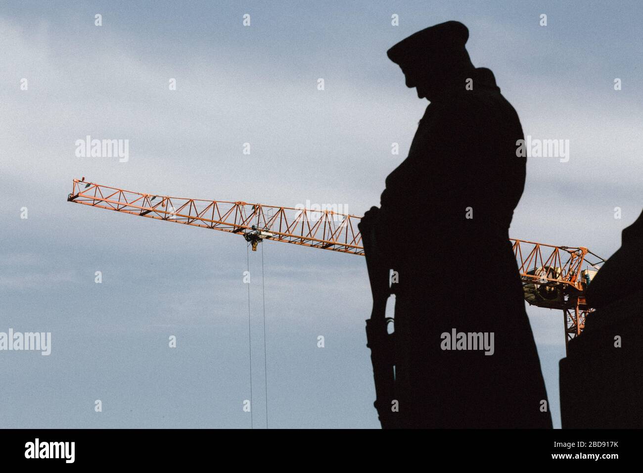 A HS2 construction crane appears behind a silhouette of the War Memorial at Euston Station Stock Photo