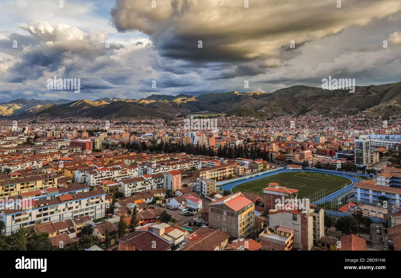 Beautiful aerial shot over the cloudy and sunny sky of Cusco, Capital of the Inca Empire, and the Inca Garcilaso de la Vega College Stadium, during th Stock Photo