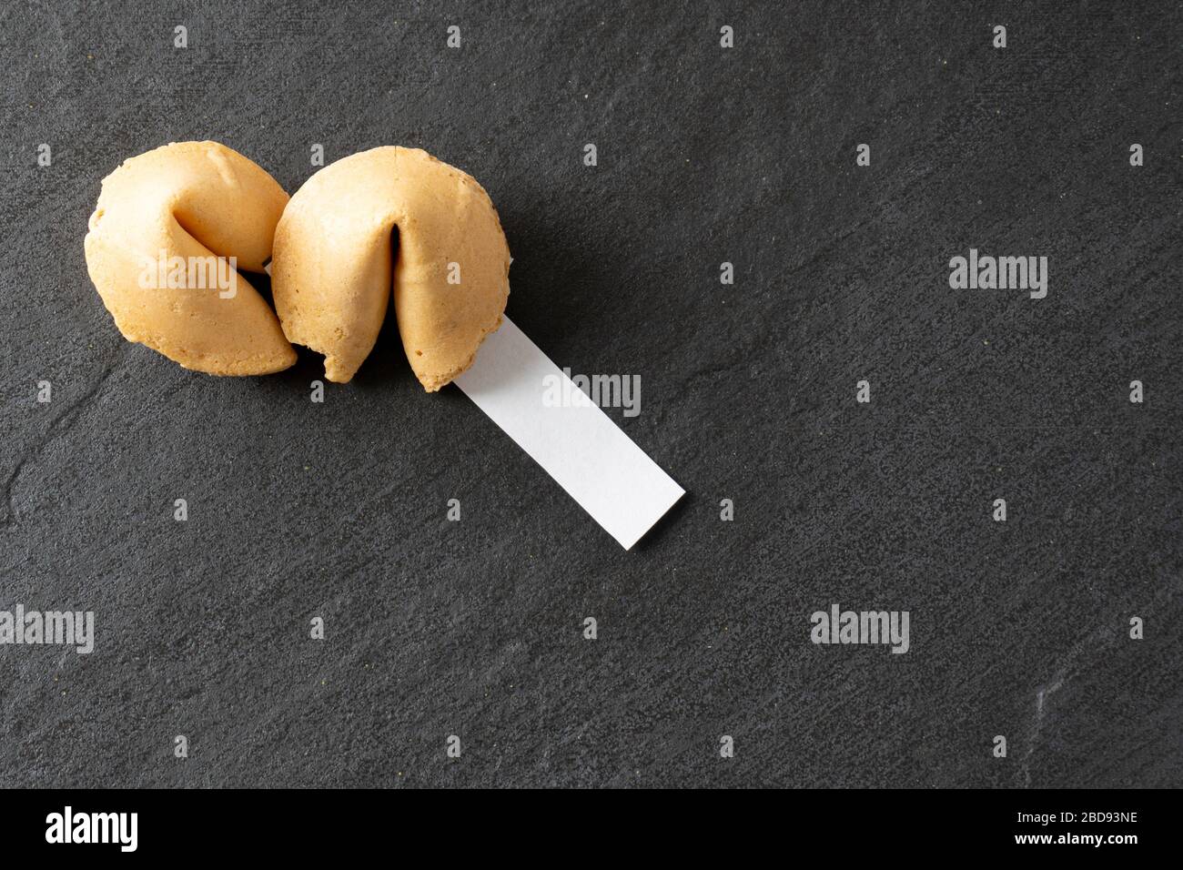 View of fortune cookies from above with a blank fortune on a black slate background with copy space; landscape view Stock Photo