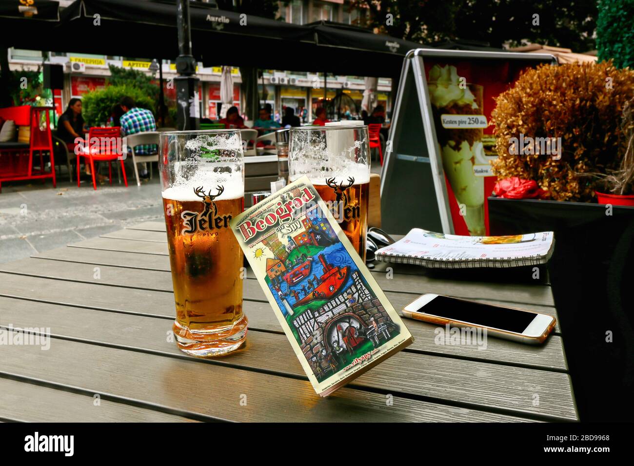 Well known local beer brand, Jelen and city guide booklet on a table at outdoor coffe/restaurant at oldtown square in Belgrade Stock Photo